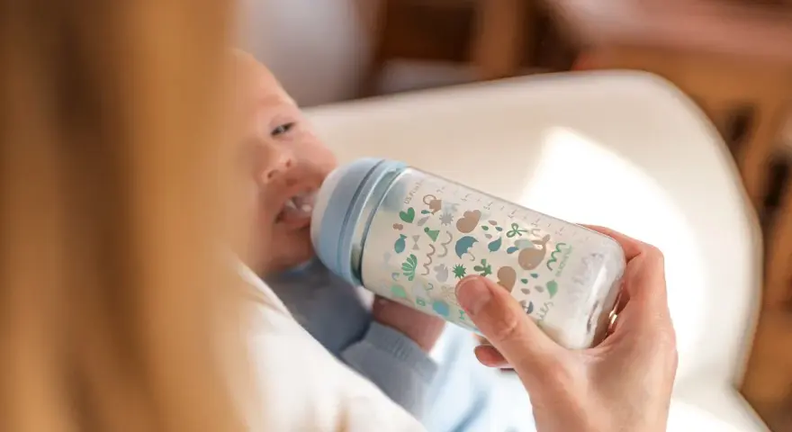 Bebé de 5 meses tomando biberón. La cantidad de biberones que toma un bebé de 5 meses varía, pero este parece disfrutar el suyo.