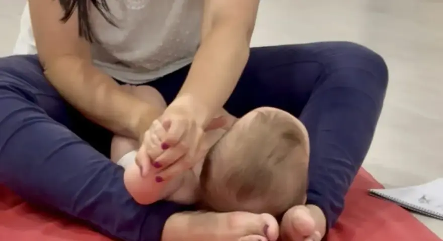 Manos cuidadosas realizan un masaje infantil en los pies de un bebé, fomentando la relajación y el vínculo.