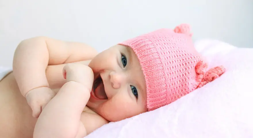 Bebé sonriente con gorro rosa, su nombre es Astrid.