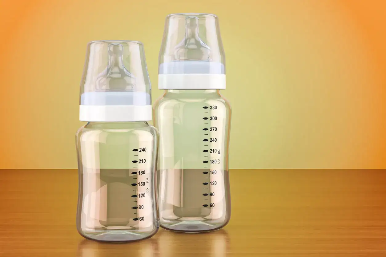 Dos biberones, uno de cristal o pl&aacute;stico m&aacute;s peque&ntilde;o y otro m&aacute;s grande, con marcas de medici&oacute;n.
