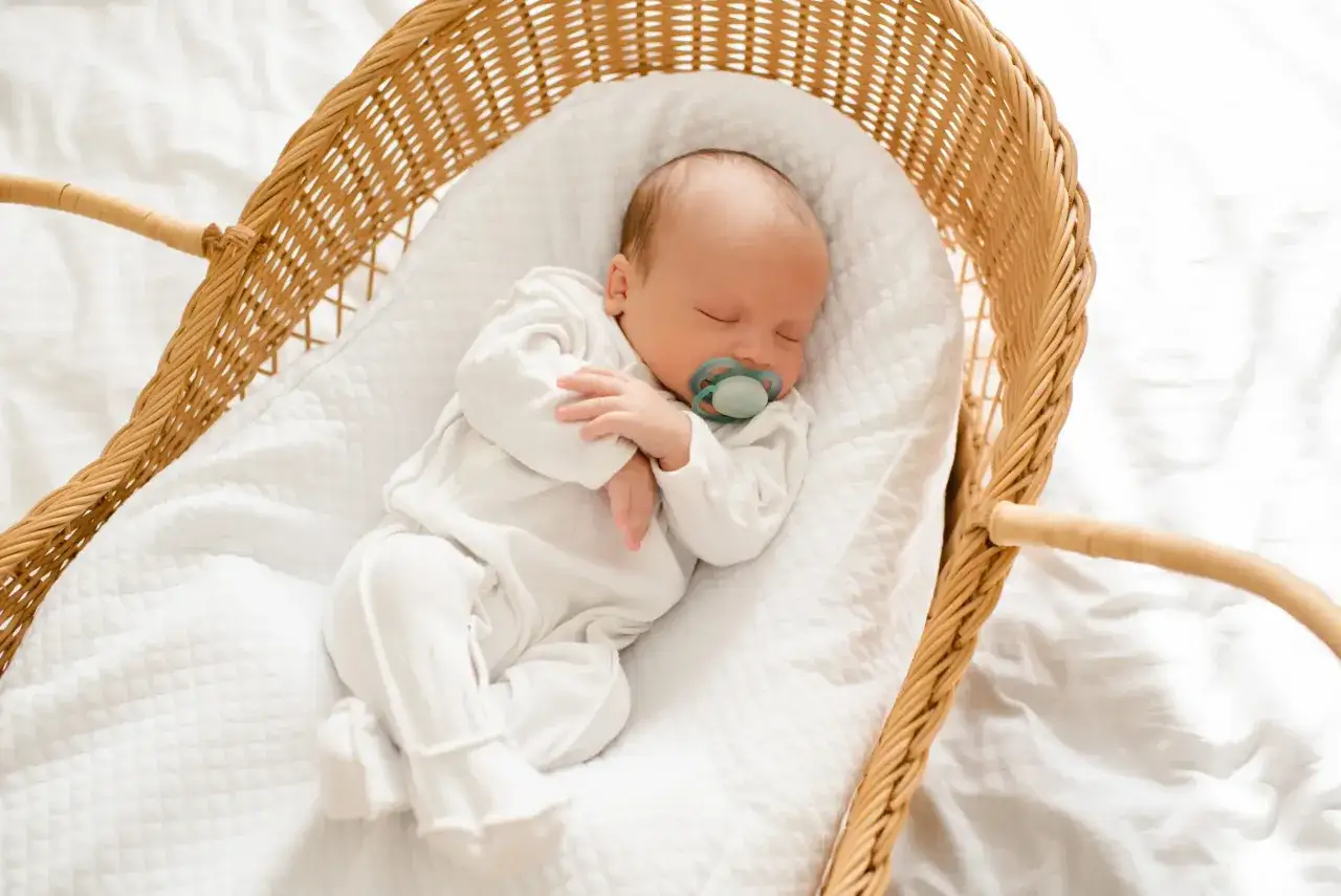 Un beb&eacute; de 6 meses duerme pl&aacute;cidamente en una cesta de mimbre, con un chupete en la boca. Su dulce sue&ntilde;o es un momento de paz.