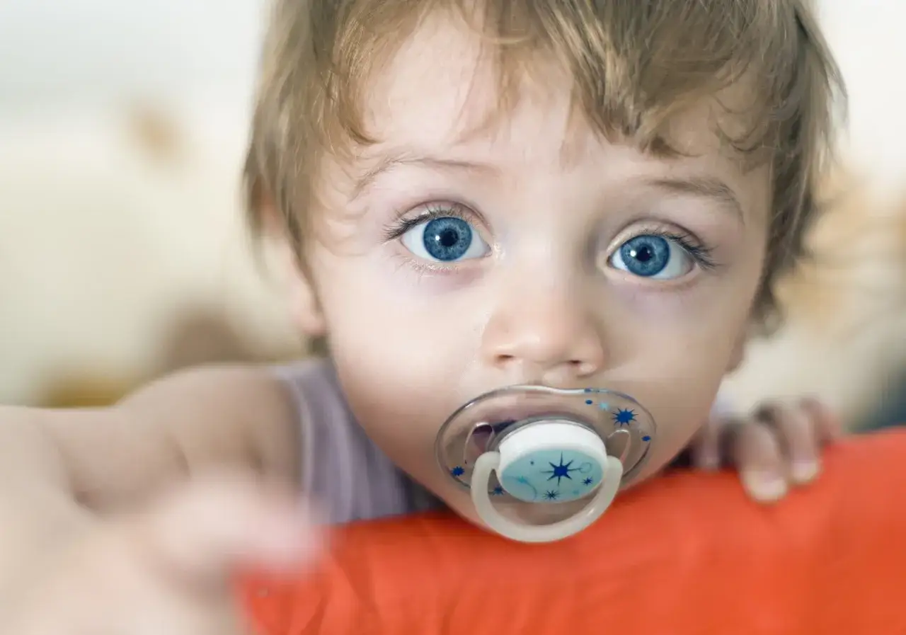 Beb&eacute; con chupete azul. Aprende c&oacute;mo esterilizar chupetes para mantenerlo limpio y seguro.