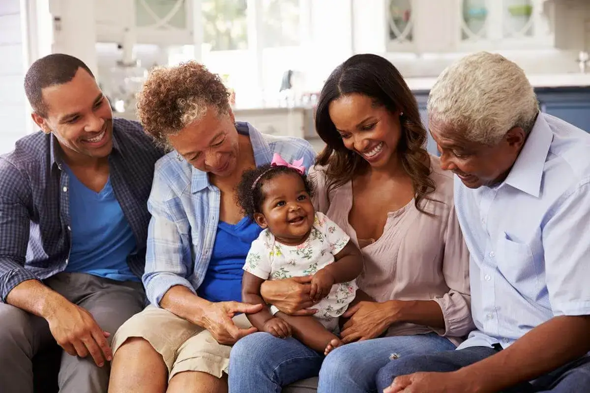 Familia multigeneracional sonr&iacute;e a un beb&eacute;, celebrando los diversos tipos de lactancia y el amor familiar.