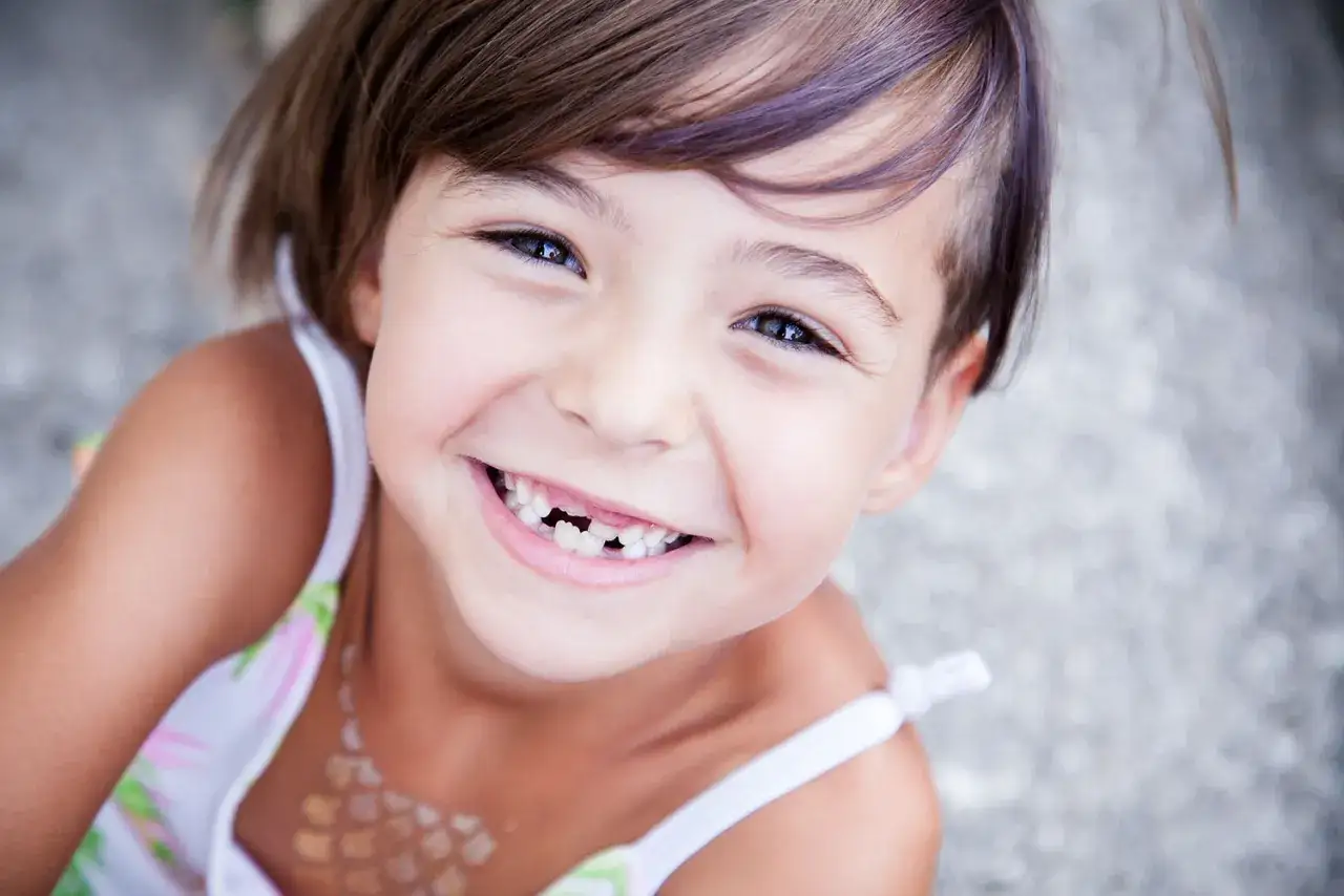 Ni&ntilde;a sonriente con agenesia dental, mostrando su peculiar sonrisa.