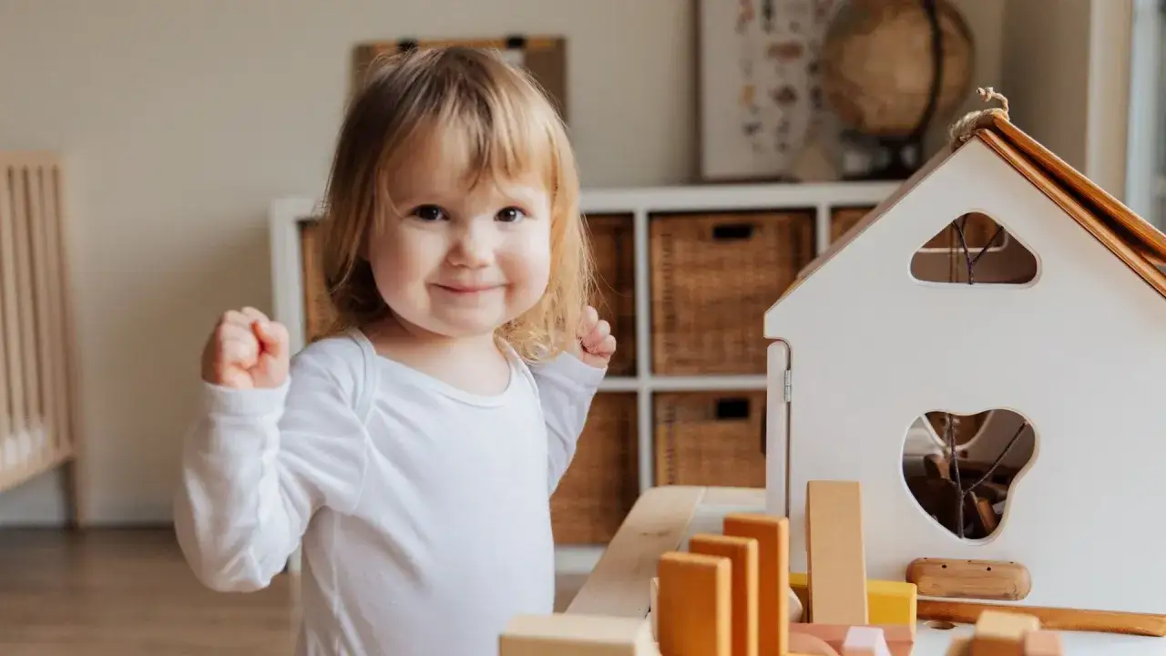 Ni&ntilde;a sonriente jugando con bloques de madera, un ejemplo de la evoluci&oacute;n del lenguaje en beb&eacute;s.