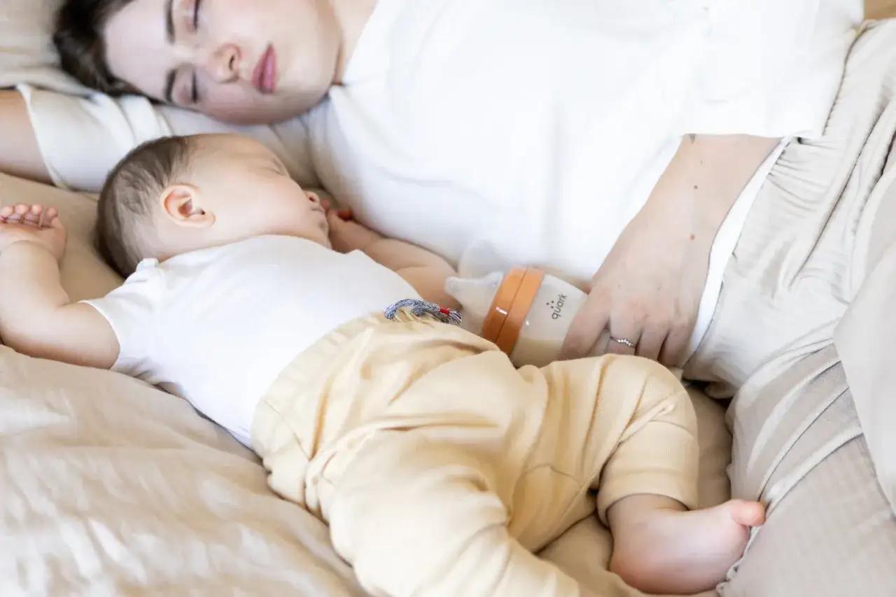 Madre e hijo duermen juntos, con un biber&oacute;n cerca. Tomas nocturnas beb&eacute; 1 mes.
