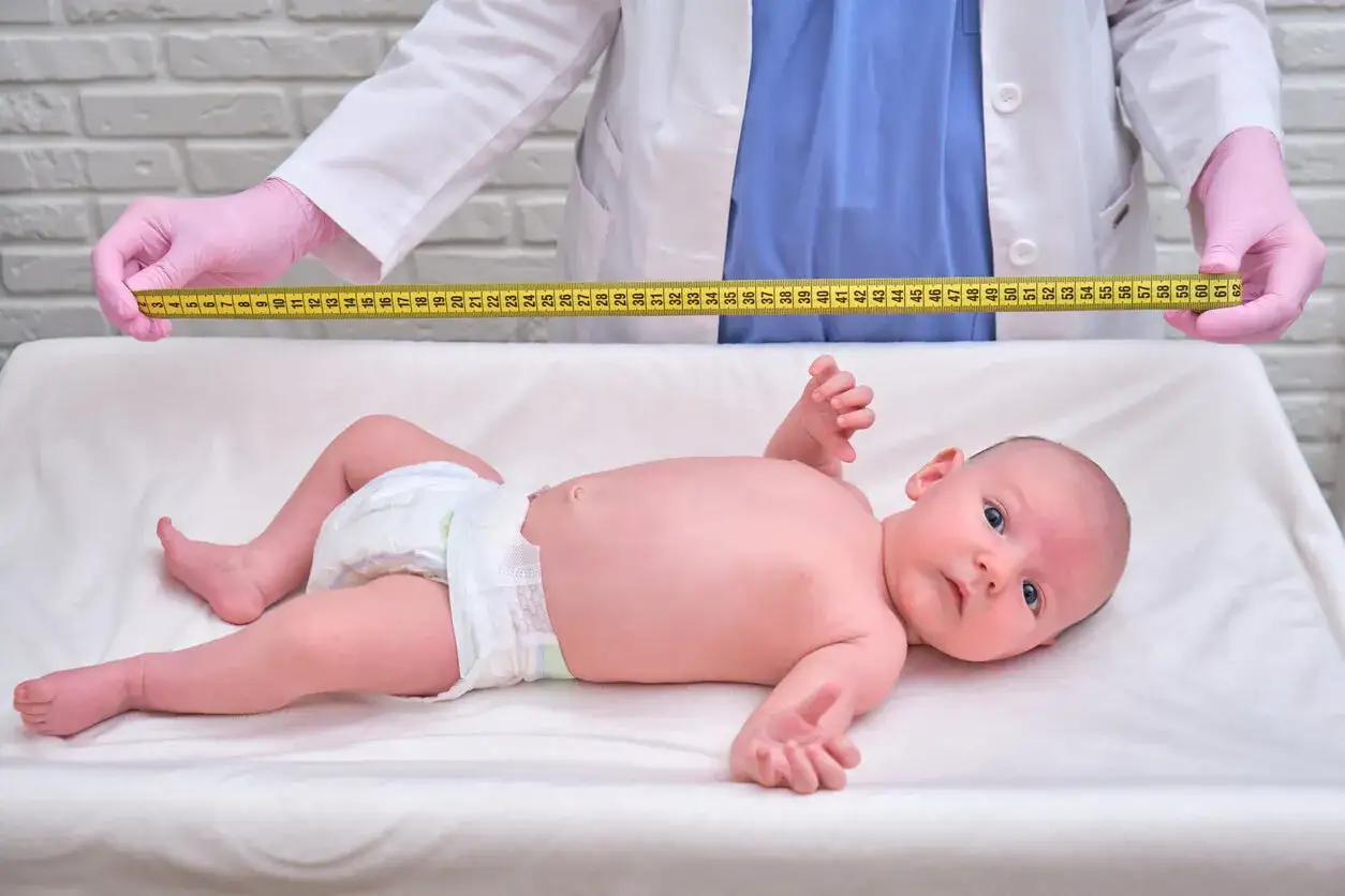 Un bebé es medido con una cinta métrica para determinar su percentil.